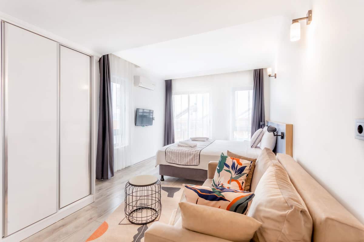 Een moderne hotelkamer met een bed, een bank, een klein rond tafeltje en een televisie.