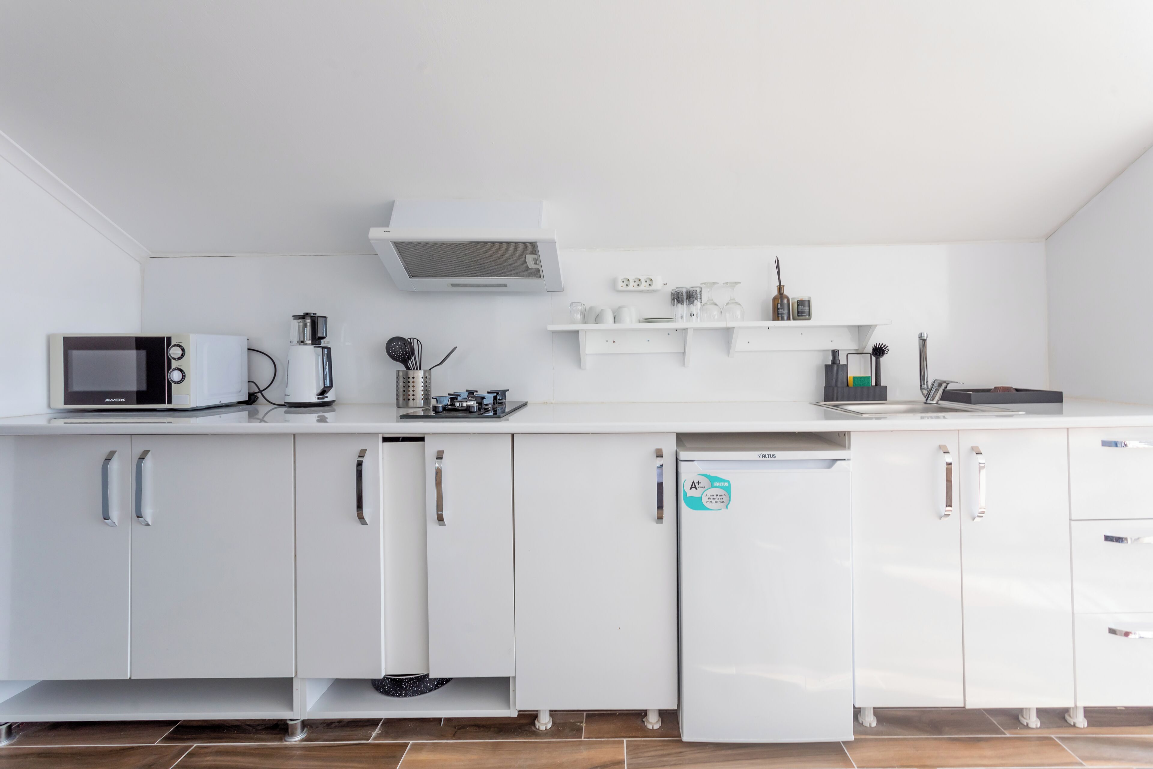 A modern kitchen with white cabinets, a microwave, a coffee maker, and a dishwasher.