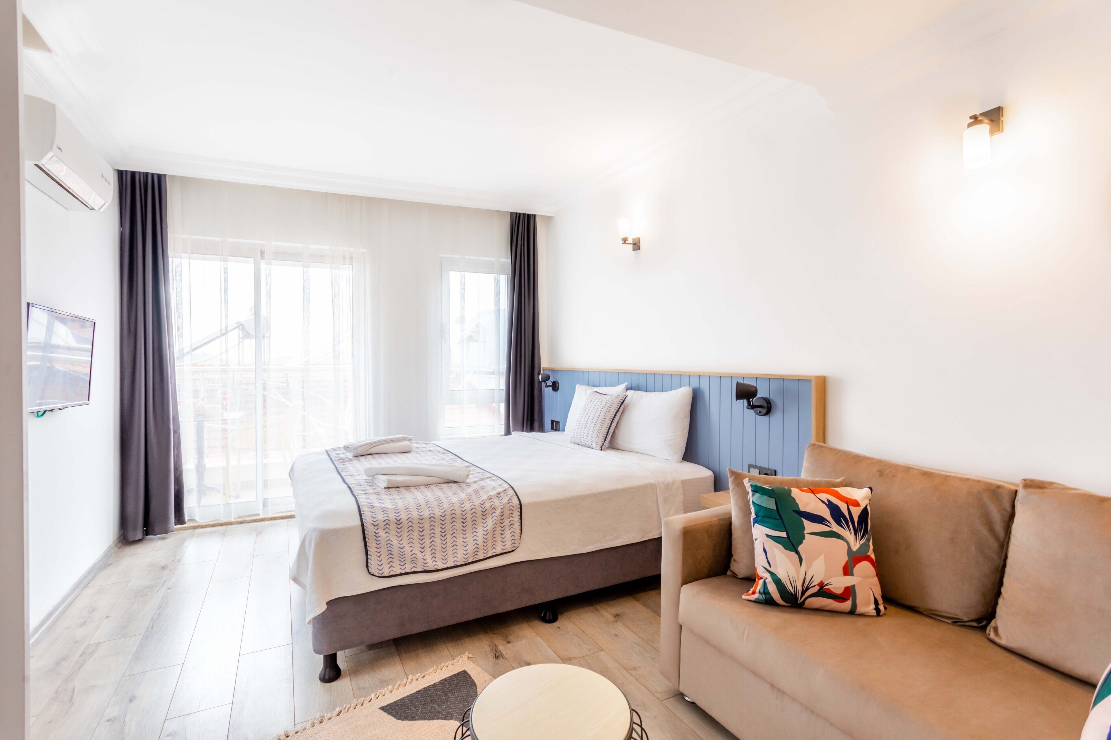 Une chambre d’hôtel moderne avec un grand lit, un canapé et une petite table ronde.