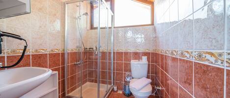 A bathroom with a shower, toilet, and sink.