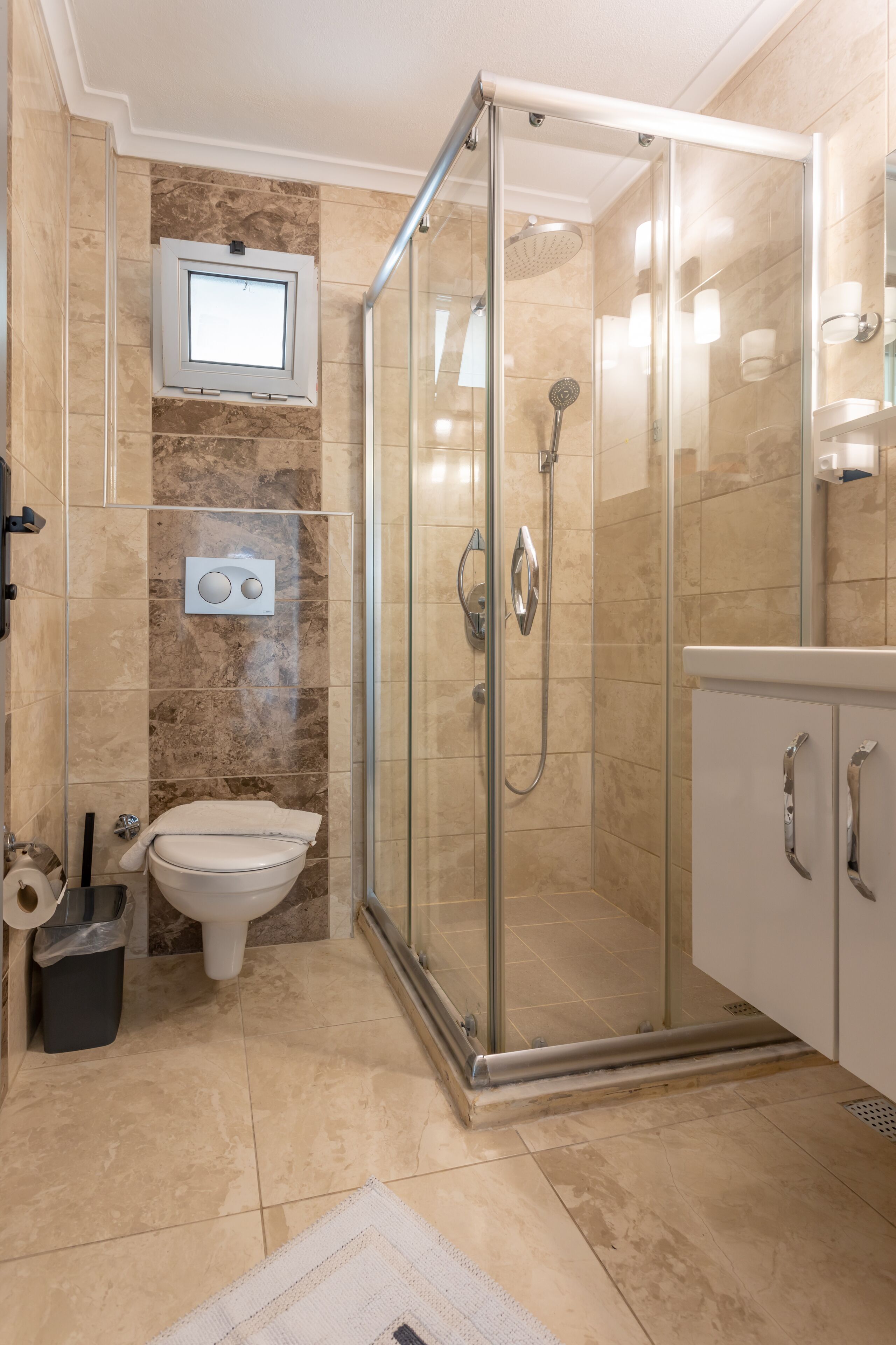 A modern bathroom with a glass-enclosed shower, a toilet, and a sink with a cabinet.