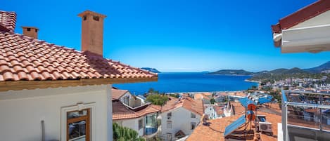 A coastal town with terracotta-tiled roofs, a sea view, and a mix of residential buildings.