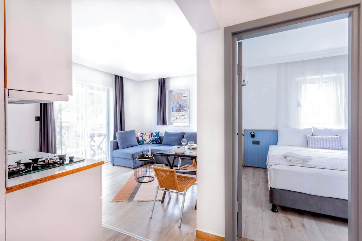 Een moderne hotelkamer met een kitchenette, een bank, een eettafel en een bed.