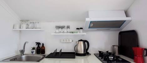 Una cucina compatta con lavandino, fornello e diversi elettrodomestici.