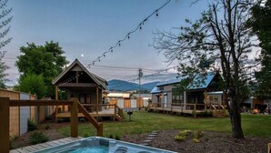 Ein Whirlpool in einem Garten mit Holzterrassen, einer überdachten Veranda und Blick auf die Berge.