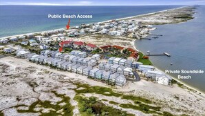 Vista aérea de uma área residencial costeira, com acesso público à praia, uma praia particular à beira do canal e um marcador de ajuste de latitude.