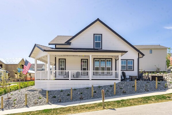 A two-story house with a covered porch, a flag, and a stone retaining wall. - Days Like This at The Lookout at Lake Chelan (Chelan)