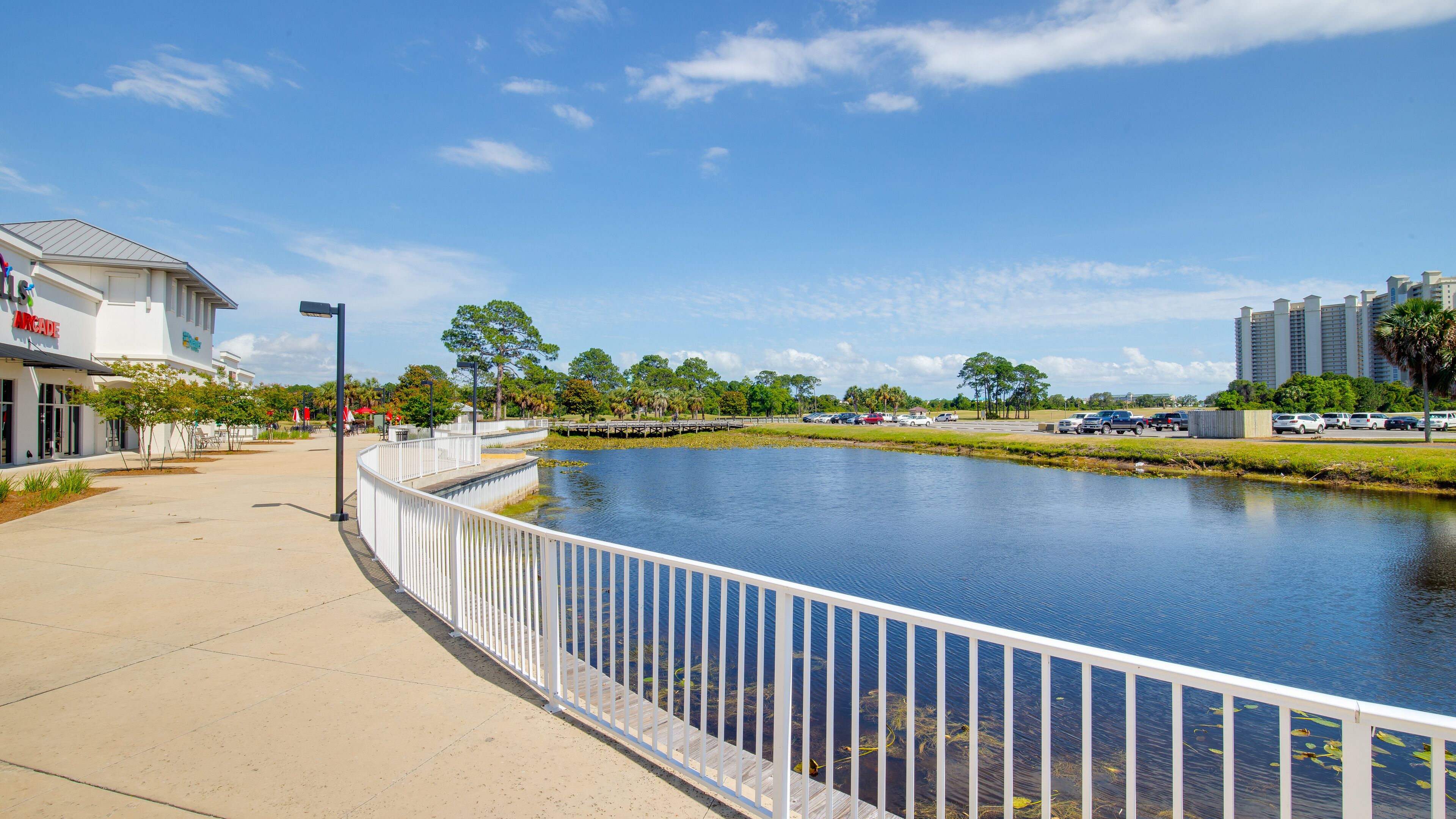 A waterfront promenade with a white fence, a boardwalk, and a building labeled "Arcade" on the left.