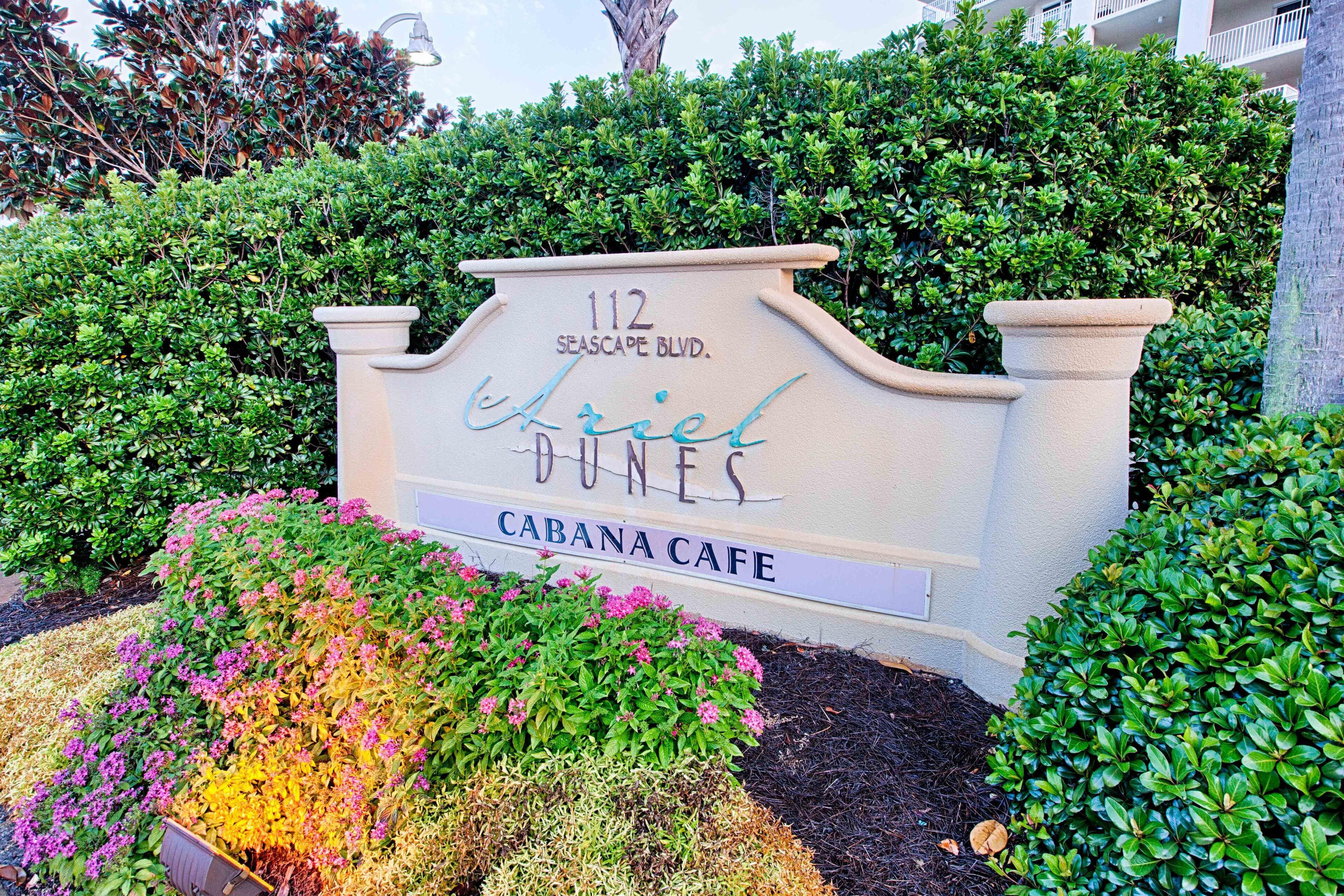 Een bord met '112 Seascape Blvd.'. 'Ariel Dunes' en 'Cabana Cafe' staan erop.