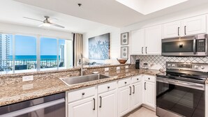 A modern kitchen with white cabinets, a stainless steel microwave, and an oven. - Seascape ~ Gulf View ~ Bunk Area (Miramar Beach)