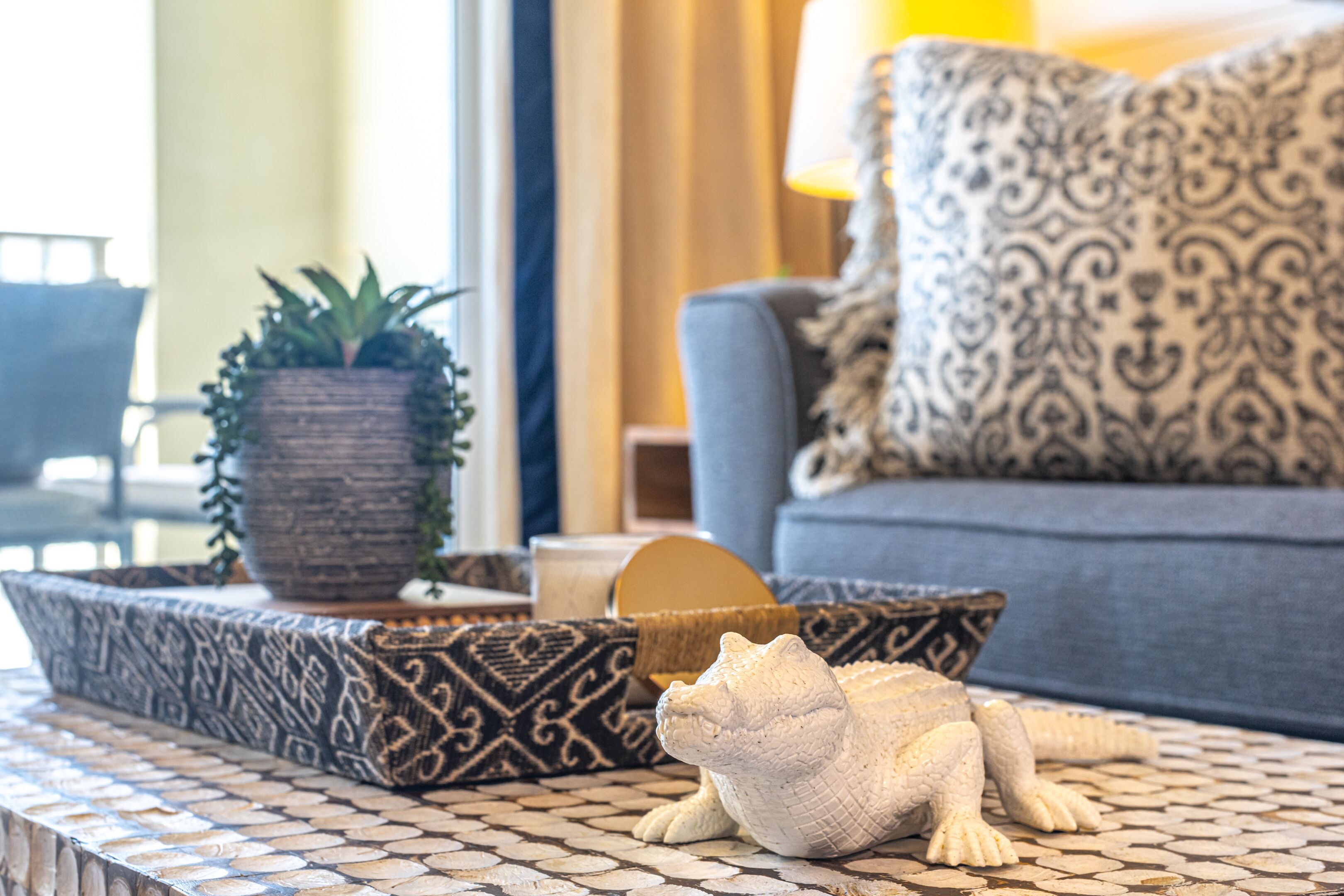 A living room with a patterned sofa, a decorative animal figurine, and a potted plant.