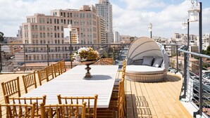 A rooftop terrace with a dining table, chairs, a decorative bowl, and a round seating area with a canopy. - ⚜ EVEN ISRAEL PENTHOUSE ⚜JACUZZI⚜5 royal Masters⚜ (jerusalem)