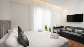 A modern hotel room with a large bed, a grey sofa, a flat-screen TV, and a small desk. - ⚜ EVEN ISRAEL PENTHOUSE ⚜JACUZZI⚜5 royal Masters⚜ (jerusalem)