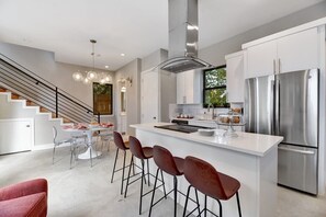 Une cuisine moderne dotée d’un îlot central, d’appareils électroménagers en acier inoxydable et d’un escalier menant à un autre niveau.