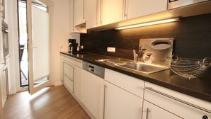 Una cocina moderna con armarios blancos, un lavamanos de acero inoxidable y una encimera oscura.