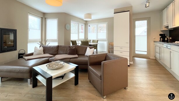 Una sala de estar moderna con un sofá seccional, una mesa de centro y un comedor con sillas.