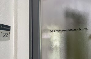 Une fenêtre en verre dépoli portant l’inscription « Wing. Meeresrauschen - n° 22 » et un numéro de porte « 22 » sur le mur.