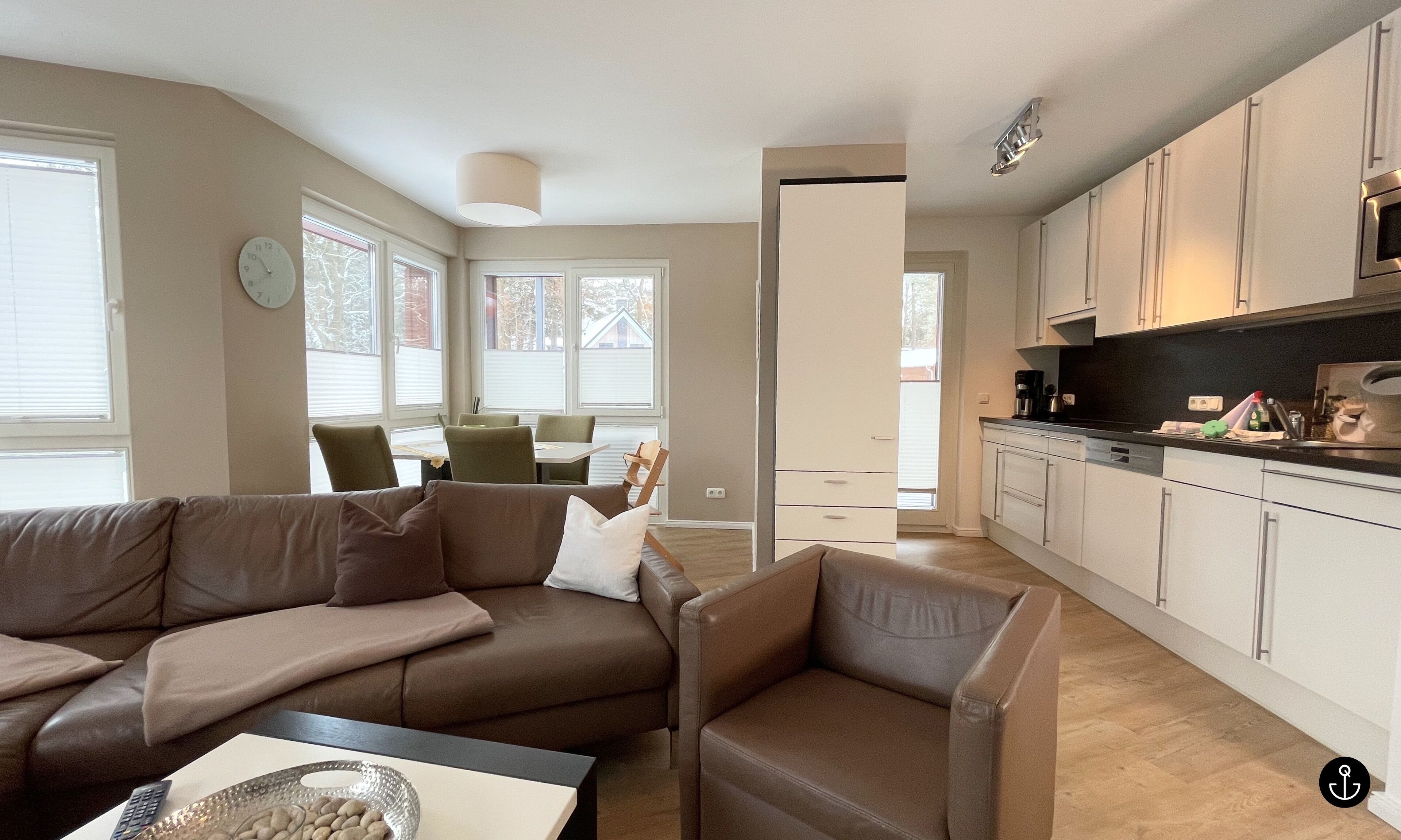 A modern living room with a brown leather sofa and a dining area with a table and chairs.