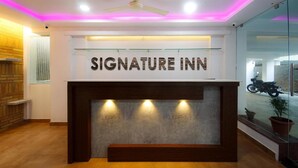Uma área de recepção com uma placa indicando "Signature Inn" acima de um balcão.