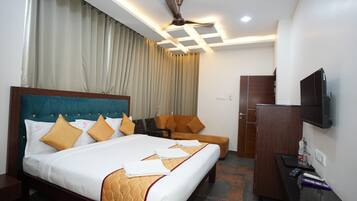 A hotel room with a large bed, a chair, a desk, and a television.
