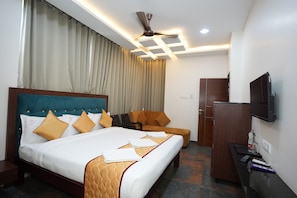 Habitación de hotel con una cama grande, una silla, un escritorio y un televisor.
