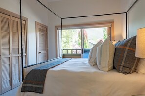 Ein Schlafzimmer mit einem Bett, Kissen, einer Lampe und Blick ins Freie.