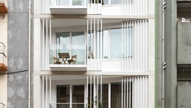 A multi-story residential building with balconies, a garage, and a visible door number.