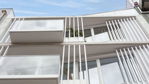 A modern building with multiple balconies, large windows, and a clear sky.