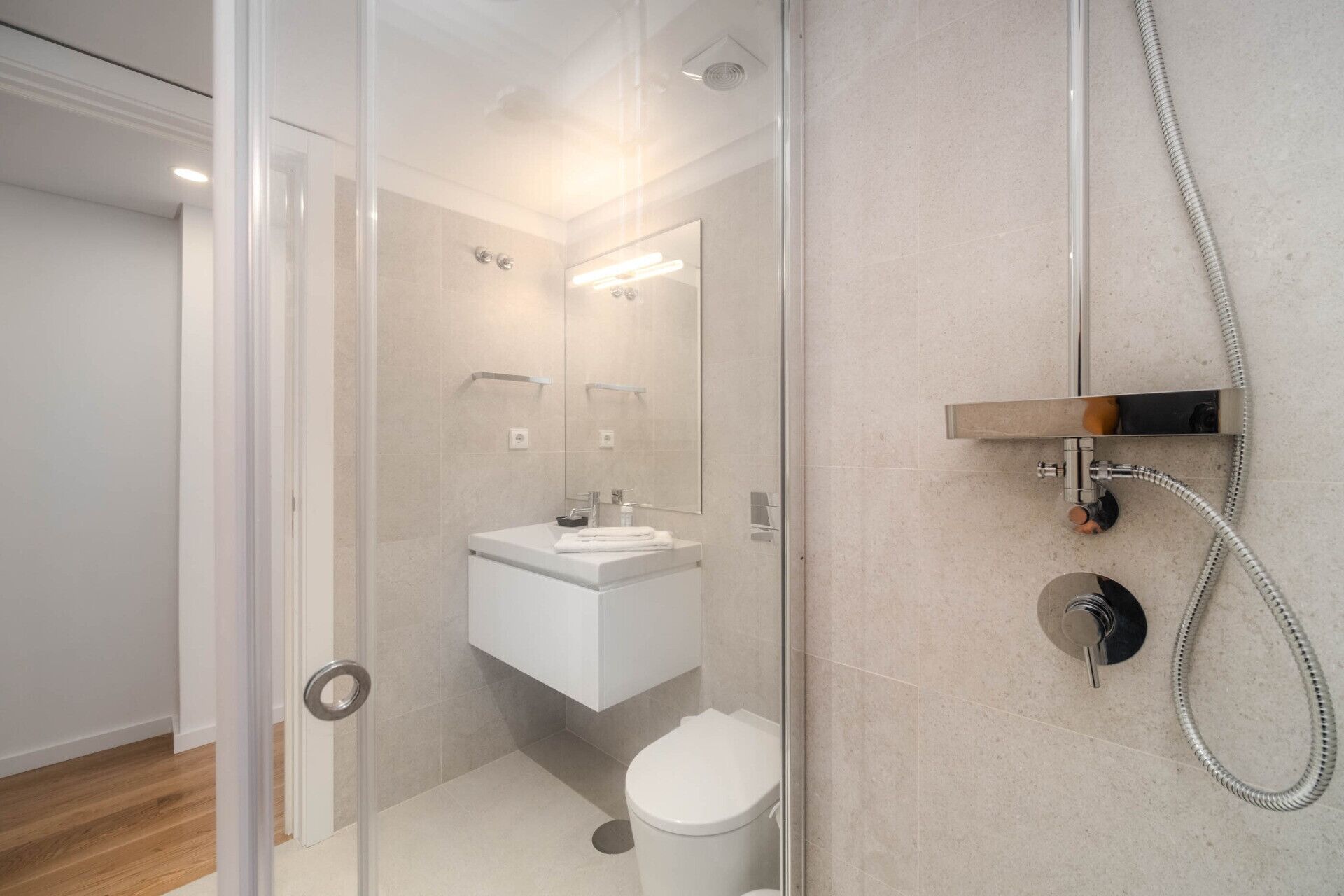 A modern bathroom with a glass shower enclosure, a white sink, and a toilet.
