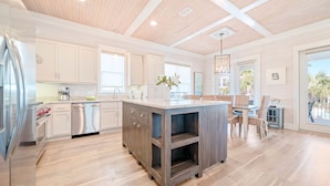 A spacious kitchen with wooden flooring, white cabinetry, and a central island. - Cottages of Romar 13 | 50 Steps to Beach Boardwalk! Amazing Home! Pool! (Orange Beach)