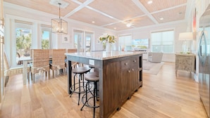 A spacious kitchen with a large island, wooden flooring, and a high ceiling with exposed beams. - Cottages of Romar 13 | 50 Steps to Beach Boardwalk! Amazing Home! Pool! (Orange Beach)
