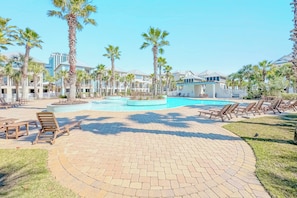 A resort pool area with lounge chairs and palm trees.