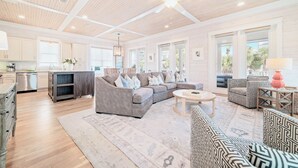 A spacious living area with a large gray sectional sofa, a round coffee table, and patterned chairs. - Cottages of Romar 13 | 50 Steps to Beach Boardwalk! Amazing Home! Pool! (Orange Beach)