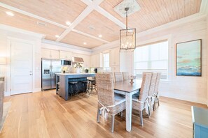 A modern kitchen with a central island, stainless steel appliances, and a dining area with wicker chairs.