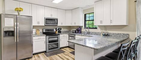 A modern kitchen with white cabinets, stainless steel appliances, and a granite countertop.