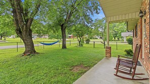 A porch with a rocking chair, a hammock, and a brick wall. - Trevor’s Riverfront Retreat w Hot Tub & Kayaks (Pigeon Forge)