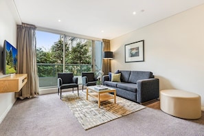 Relax in this stylish living room with a balcony offering views of lush surroundings and cityscape.