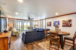 A spacious living area with a dark blue sectional sofa, a wooden dining table with chairs, and a ceiling fan. - 601C is a Gorgeous 2 BR with Boat Slip (Destin)