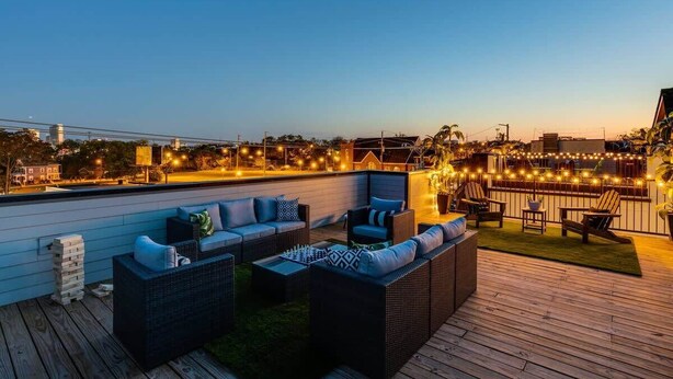 Una terraza en la azotea con mesas al aire libre y luces colgantes.