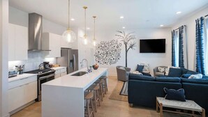 Una cocina moderna con una isla central, taburetes de bar e iluminación colgante.
