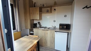 A compact kitchen with wooden cabinets, a white refrigerator, a microwave, and a small sink. - House with garden 2 bedrooms Soulac Sur Mer 500m from the beach (Soulac-sur-Mer)