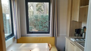 A compact kitchen with a wooden table and chairs, a built-in bench, and a window overlooking greenery. - House with garden 2 bedrooms Soulac Sur Mer 500m from the beach (Soulac-sur-Mer)