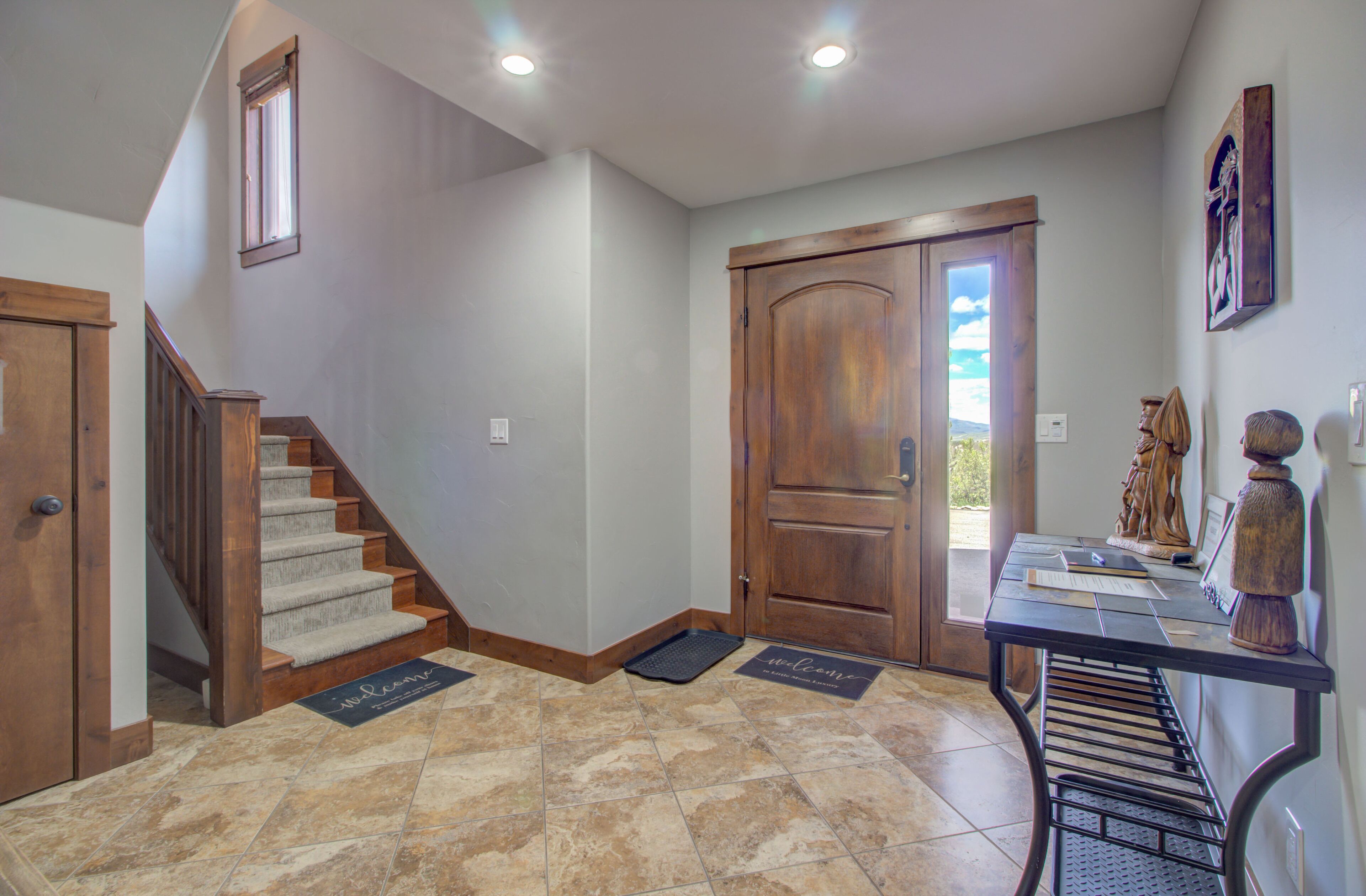 A home interior with a staircase, wooden door, and a welcome mat.