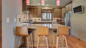A modern kitchen with wooden cabinets, a large island with bar stools, and pendant lighting.