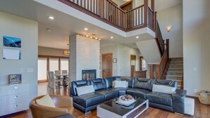 A spacious living room with a large sectional sofa, a coffee table, and a staircase leading to an upper level.