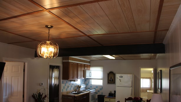 Una cocina amplia con vigas de madera en el techo, una araña y un comedor con mesa y sillas.