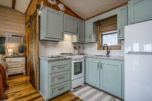 Compact kitchen with oven, sink, and refrigerator.
