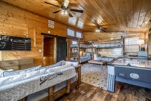 Relax in a cozy cabin-style room with a hot tub, sofa, and two single beds.