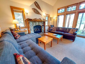 A living room with a stone fireplace, a sofa, a coffee table, and a leather couch.