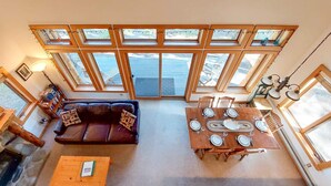 Una habitación amplia con una gran mesa de comedor, un sofá y varios ventanales que dejan entrar luz natural.